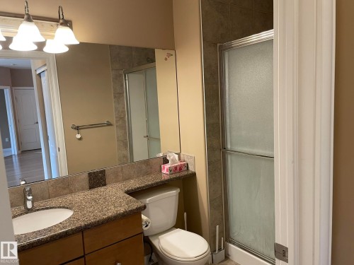 Well-appointed bathroom featuring a vanity with a granite countertop, an integrated sink, a large mirror, and a shower with a sliding glass door - Edmonton, AB - Indoor Photo Showing Bathroom