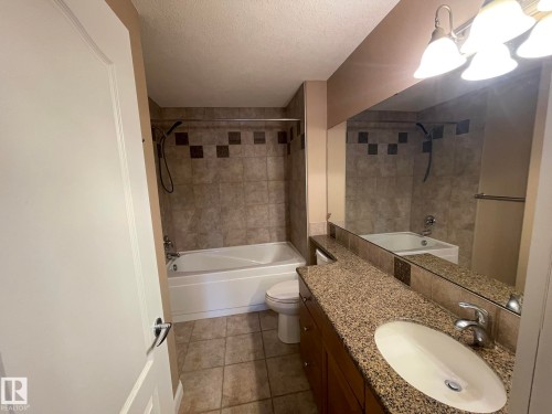Bathroom featuring a vanity with a granite countertop, an integrated sink, and a large mirror - Edmonton, AB - Indoor Photo Showing Bathroom