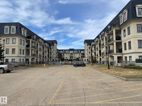 Contemporary apartment buildings featuring balconies and dormer windows, set around a paved parking area - Edmonton, AB - Outdoor With Facade