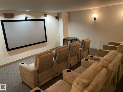 Dedicated media room featuring a large projection screen, wall-mounted speakers, and comfortable tiered seating - Edmonton, AB - Indoor Photo Showing Other Room