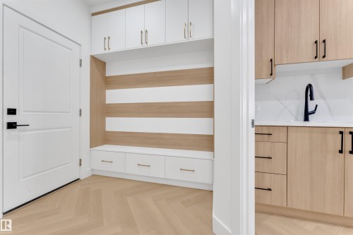 Entryway featuring built-in storage with white cabinetry, a bench with drawers, and light hardwood flooring in a herringbone pattern - 12 Dalquist Bay, Leduc, AB - Indoor