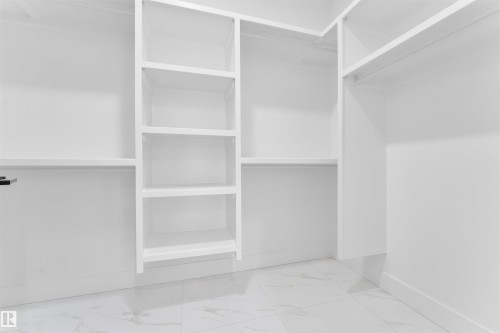 The property features a spacious closet with built-in shelving and hanging rods, finished in white - 12 Dalquist Bay, Leduc, AB - Indoor With Storage