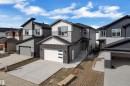 The property features a modern exterior with grey siding and dark brick accents, a front-facing garage with a contemporary door design, and a concrete driveway - 12 Dalquist Bay, Leduc, AB  - Outdoor With Facade 