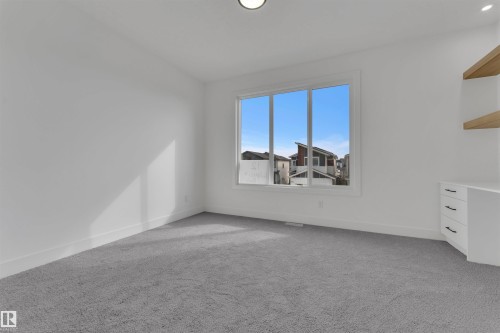 This room features light grey carpeting, white walls, and a large window providing ample natural light - 12 Dalquist Bay, Leduc, AB - Indoor Photo Showing Other Room