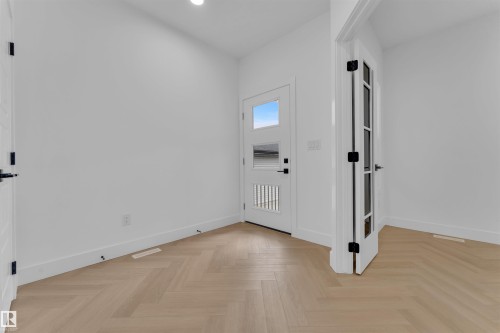 The room features light-colored herringbone flooring and a white door with frosted glass panels - 12 Dalquist Bay, Leduc, AB - Indoor Photo Showing Other Room