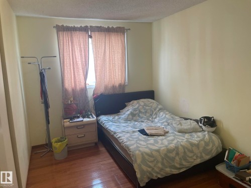 Interior space featuring wood-finish flooring, light-toned walls, and a window with drapery - 9320 175 Street, Edmonton, AB - Indoor Photo Showing Bedroom