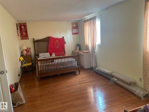 Spacious room featuring wood-finish flooring, light-colored walls, and a window with natural light - 9320 175 Street, Edmonton, AB - Indoor Photo Showing Bedroom