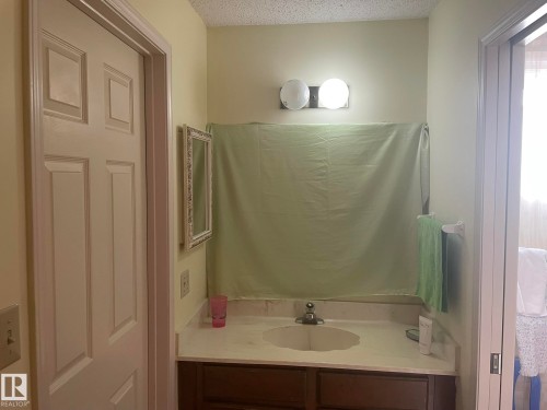 Bathroom vanity with a light-toned countertop, integrated sink, and wood-finish cabinetry - 9320 175 Street, Edmonton, AB - Indoor Photo Showing Bathroom
