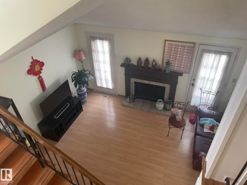 Living room featuring a fireplace with a dark wood mantel and tile surround, wood-finish flooring, and two exterior doors with glass panels - 9320 175 Street, Edmonton, AB - Indoor Photo Showing Living Room With Fireplace