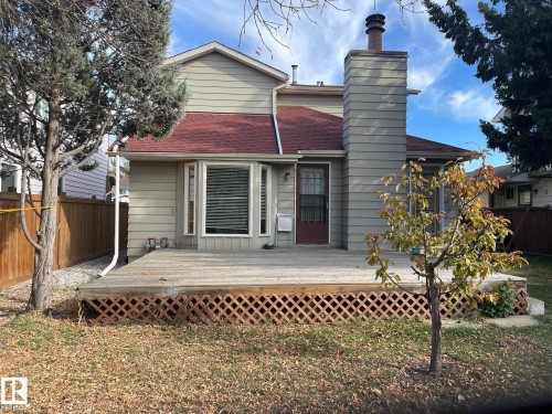 The property features a spacious deck with lattice detailing, a red roof, and a prominent chimney - 9320 175 Street, Edmonton, AB - Outdoor With Deck Patio Veranda