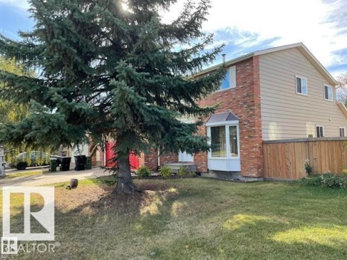 The property features a brick and siding exterior with a bay window, a manicured lawn, and mature trees - 9320 175 Street, Edmonton, AB - Outdoor