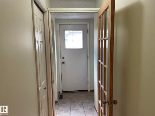 Entryway featuring tile flooring, a white exterior door with a window, and a wooden interior door with glass panes - 9320 175 Street, Edmonton, AB - Indoor Photo Showing Other Room