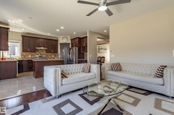The property features an open-concept living area with a ceiling fan, a patterned area rug, and light-colored walls - 