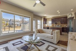 Open concept living space featuring large windows, a ceiling fan, and hardwood flooring - 