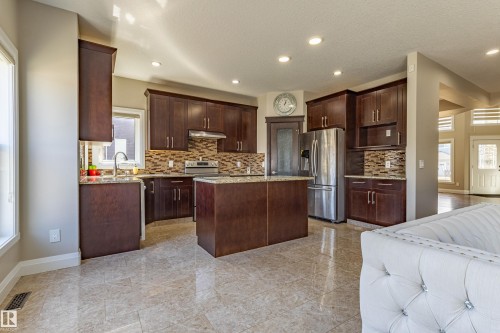 The kitchen features dark wood cabinetry, a central island, stainless steel appliances, and a tiled backsplash - 3611 14 Street, Edmonton, AB - Indoor Photo Showing Kitchen With Upgraded Kitchen