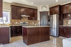 Kitchen featuring dark wood cabinetry, granite countertops, stainless steel appliances, and a tiled backsplash - 