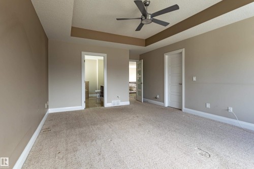 This room features a tray ceiling with a ceiling fan, carpeted flooring, and a white paneled door - 3611 14 Street, Edmonton, AB - Indoor Photo Showing Other Room