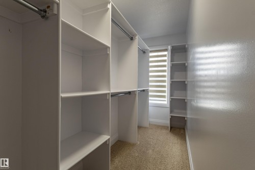 The property features a walk-in closet with built-in shelving, hanging rods, and a window with horizontal blinds - 3611 14 Street, Edmonton, AB - Indoor With Storage