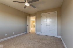 This room features plush carpeting, a modern ceiling fan, and white baseboards - 