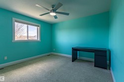 This room features a window providing natural light, a ceiling fan with integrated lighting, and carpeted flooring - 