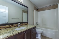 Well-appointed bathroom featuring a vanity with a granite countertop, a rectangular undermount sink, and a large mirror - 