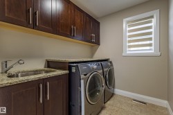 Laundry area with rich wood cabinetry, a granite countertop, and a stainless steel sink with a pull-down faucet - 