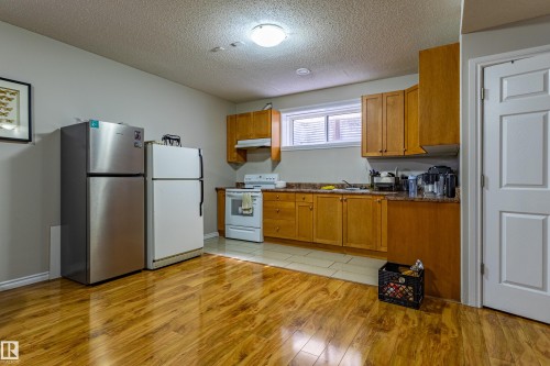 The kitchen features wood cabinetry, a window with blinds, and a white refrigerator and range - 3611 14 Street, Edmonton, AB - Indoor Photo Showing Kitchen