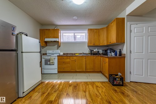 Kitchen featuring wood cabinetry, white appliances, a window with blinds, and hardwood style flooring - 3611 14 Street, Edmonton, AB - Indoor Photo Showing Kitchen