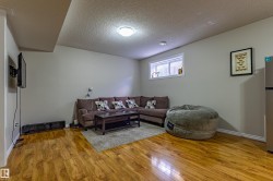 This living area features rich wood flooring, a window providing natural light, and neutral wall paint - 