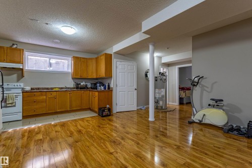 Kitchen area featuring wood cabinetry, a white stove, and a window with blinds - 3611 14 Street, Edmonton, AB - Indoor Photo Showing Other Room