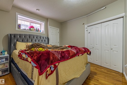 This room features wood flooring, a window with white trim, and white bi-fold closet doors - 3611 14 Street, Edmonton, AB - Indoor Photo Showing Bedroom