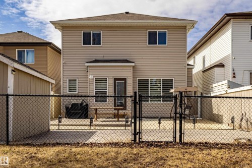 The property features light-colored siding, a brown roof, and a fenced backyard with a concrete patio - 3611 14 Street, Edmonton, AB - Outdoor With Deck Patio Veranda With Exterior