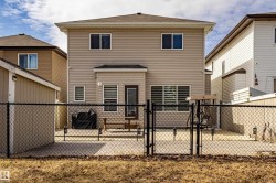 The property features light-colored siding, a brown roof, and a fenced backyard with a concrete patio - 