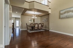 The property features hardwood floors, a formal dining area with a chandelier, and an open entryway with a high ceiling and a staircase - 