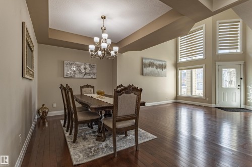 The property features rich hardwood flooring throughout, a chandelier over the dining area, and large windows providing natural light - 3611 14 Street, Edmonton, AB - Indoor Photo Showing Dining Room
