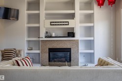 Living room featuring a fireplace with a stone surround, built-in shelving, and a wall-mounted television - 