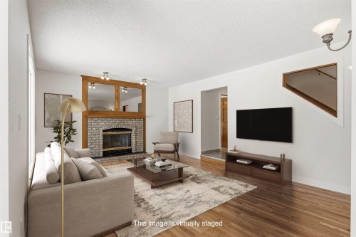 The living room features hardwood flooring, a fireplace with a stone surround, and a decorative wooden mantel with mirrors - 3668 31A Street, Edmonton, AB - Indoor Photo Showing Living Room With Fireplace