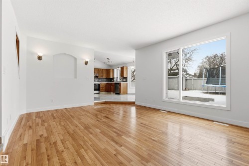 This bright room features hardwood flooring and a large window overlooking the backyard - 3668 31A Street, Edmonton, AB - Indoor Photo Showing Living Room