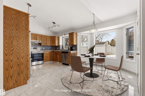 Kitchen featuring wood cabinetry, stainless steel appliances, and a tiled backsplash - 3668 31A Street, Edmonton, AB - Indoor