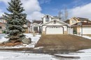 The property features a two-story exterior with white siding and a brown roof, a prominent front-facing garage, and an established evergreen tree in the front yard - 3668 31A Street, Edmonton, AB  - Outdoor With Facade 