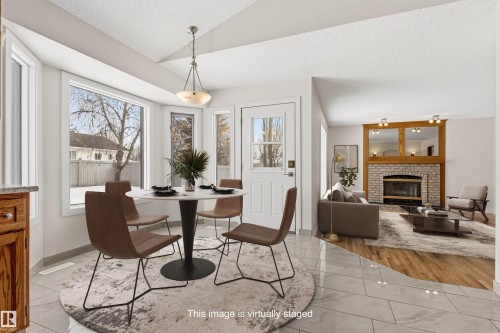 The dining area features large windows, a tiled floor, and a modern chandelier - 3668 31A Street, Edmonton, AB - Indoor Photo Showing Dining Room With Fireplace