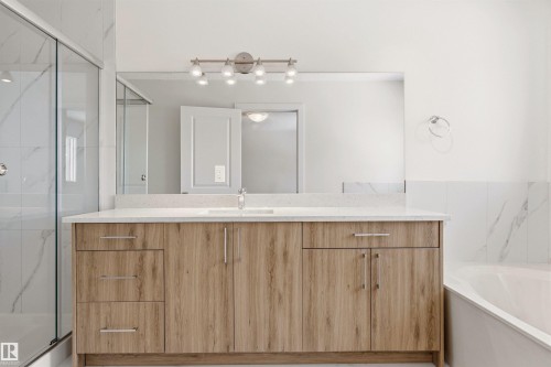 Bathroom featuring a spacious vanity with light wood finish cabinetry, a quartz countertop, and a large mirror with overhead lighting - 3668 31A Street, Edmonton, AB - Indoor Photo Showing Bathroom