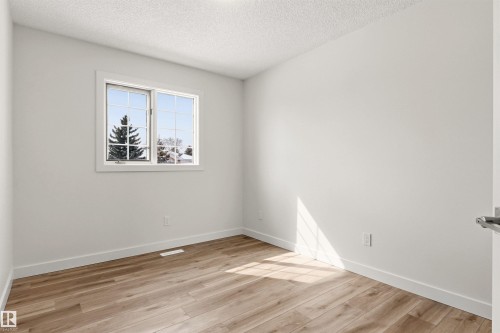 This room features light-colored walls, wood-style flooring, and a window with white trim - 3668 31A Street, Edmonton, AB - Indoor Photo Showing Other Room