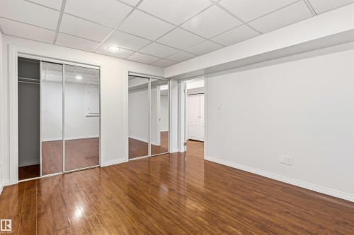 Spacious room featuring rich hardwood flooring, mirrored sliding closet doors, and recessed lighting - 3668 31A Street, Edmonton, AB - Indoor Photo Showing Other Room