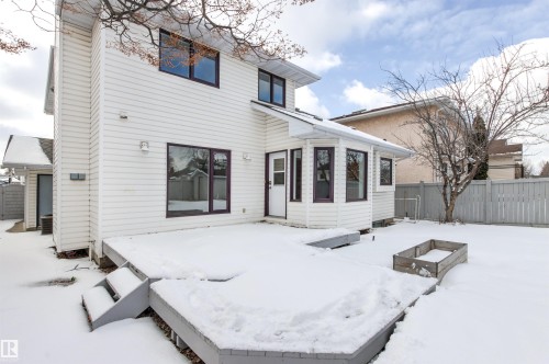 The property features a white exterior with dark-framed windows, a multi-level deck, and a fenced yard with a raised planter box - 3668 31A Street, Edmonton, AB - Outdoor