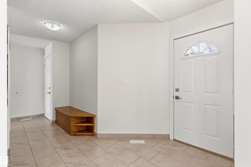Entryway featuring light-toned tile flooring, white walls, and a white front door with an arched window - 3668 31A Street, Edmonton, AB - Indoor Photo Showing Other Room