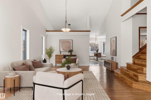 Living room featuring hardwood flooring, high vaulted ceilings, and a wooden staircase - 3668 31A Street, Edmonton, AB - Indoor Photo Showing Living Room
