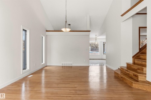 Spacious living area featuring polished hardwood floors, soaring vaulted ceilings, and large windows that provide ample natural light - 3668 31A Street, Edmonton, AB - Indoor Photo Showing Other Room