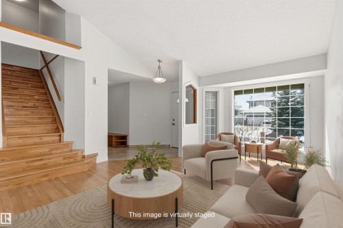 Bright living space featuring hardwood floors, a bay window, and a wooden staircase - 3668 31A Street, Edmonton, AB - Indoor Photo Showing Living Room