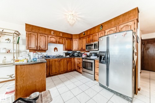 Kitchen featuring wood cabinetry, white tile flooring, and stainless steel appliances - 208 Willow Crescent, Wetaskiwin, AB - Indoor Photo Showing Kitchen